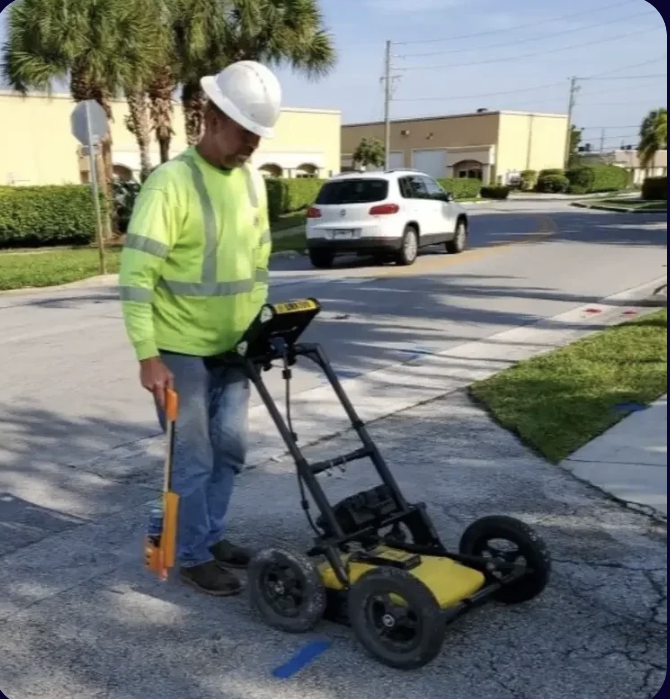 GPR technician pushing ground penetrating radar cart on pavement for underground utility scanning — South Florida GPR contractor