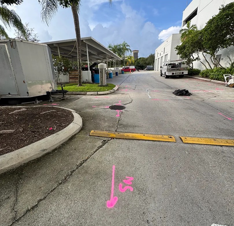 Sanitary sewer line marked with a direction arrow during a private utility locate on a commercial drive in South Florida